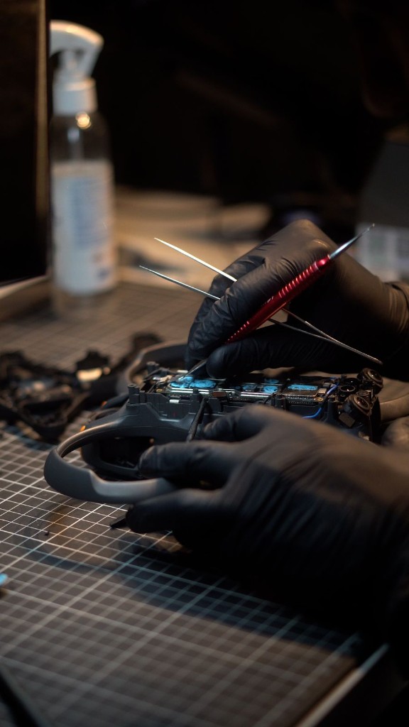 Técnico realizando reparo em placa de drone com ferramentas de precisão